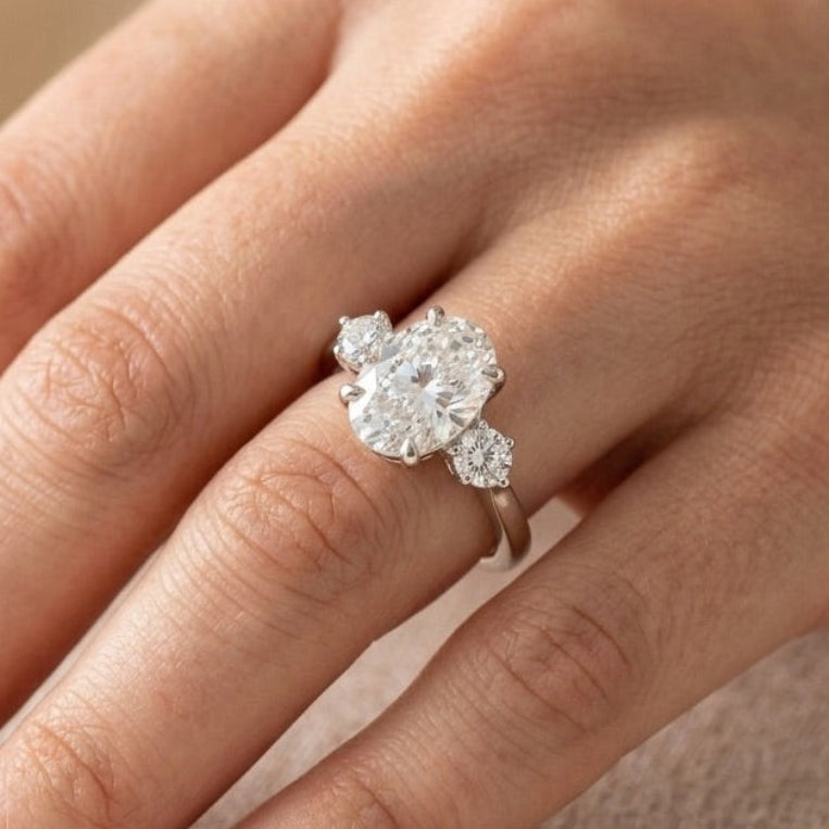 Oval cut moissanite three stone engagement ring in 14K white gold with VVS colorless center stone