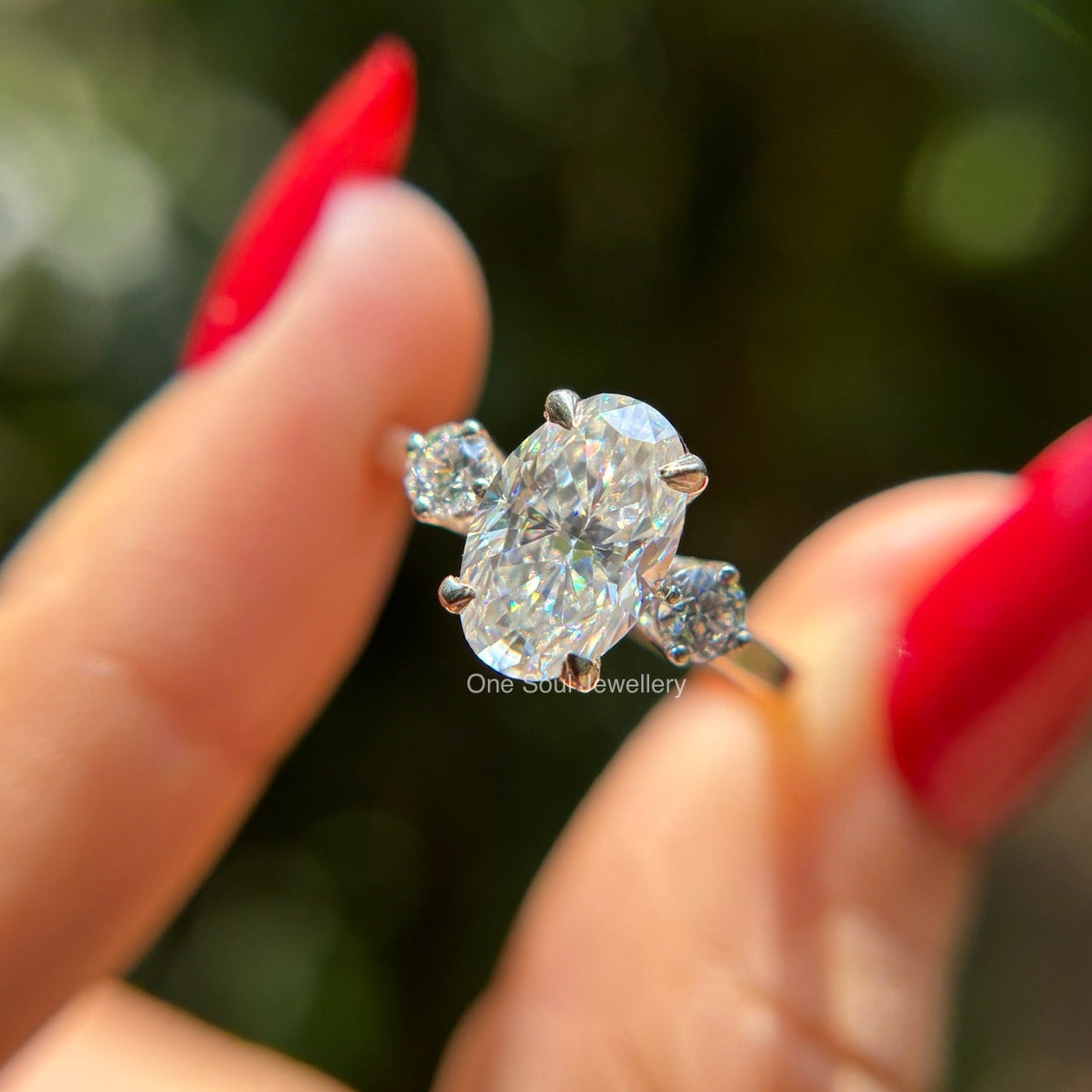 Oval cut moissanite three stone engagement ring in 14K white gold with VVS colorless center stone