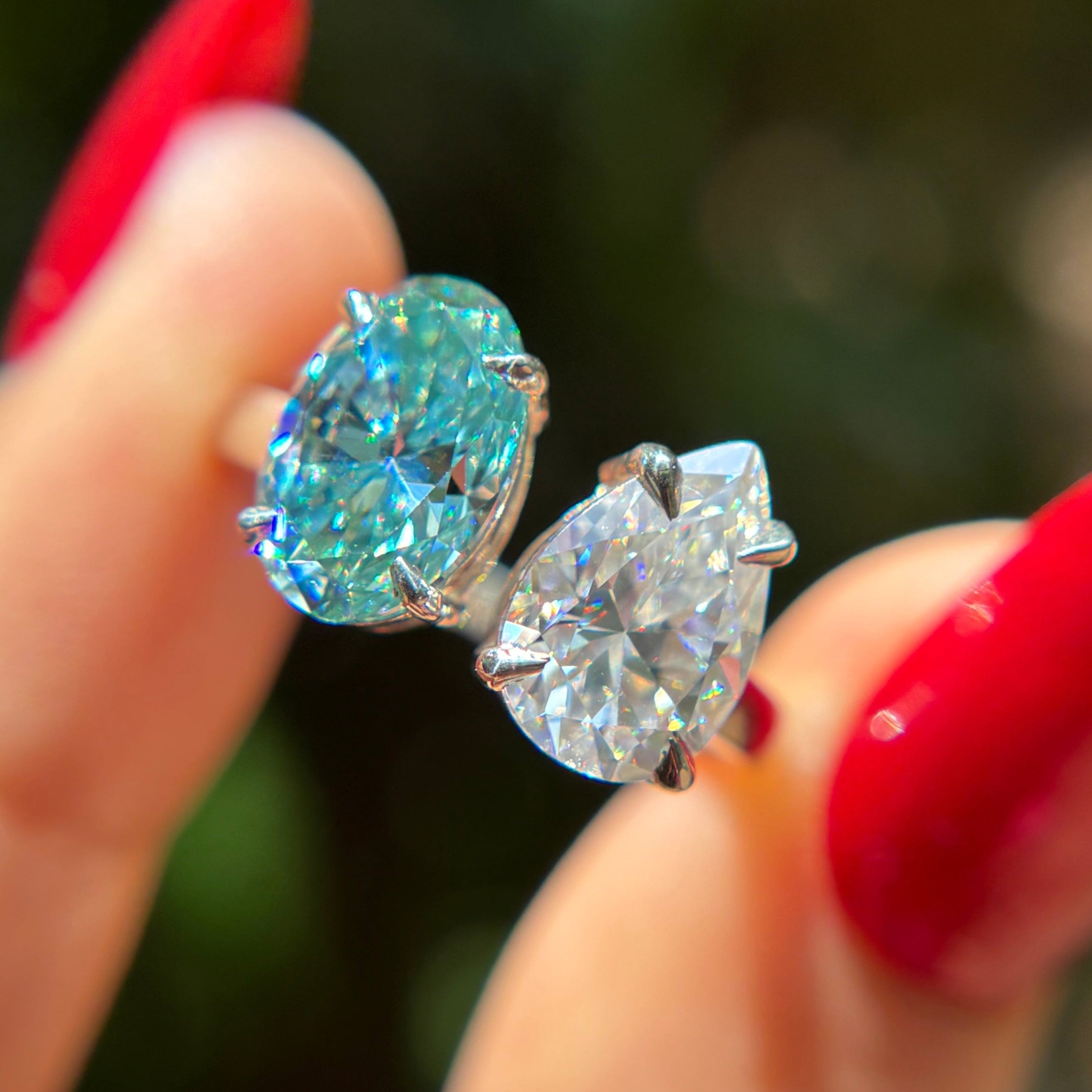 Toi et moi engagement ring with cyan blue oval moissanite and colorless pear moissanite in 14K white gold